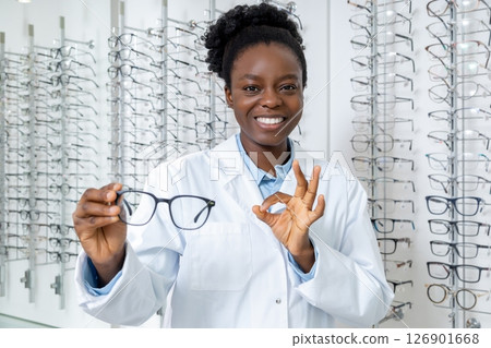 Smiling dark-skinned optician presenting new model of eyeglasses 126901668