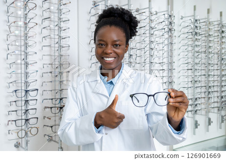Smiling dark-skinned optician presenting new model of eyeglasses 126901669