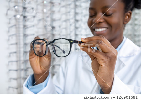 African american optometrist in a lab coat holding new eyeglasses in hands 126901681