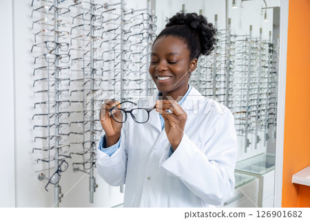 African american optometrist in a lab coat holding new eyeglasses in hands 126901682