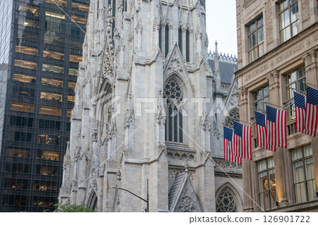 A close-up view of the ornate facade of St. Patrick's Cathedral on 5th Avenue in Manhattan. American flags hang proudly from the building opposite, highlighting New York's patriotic and architectural 126901722