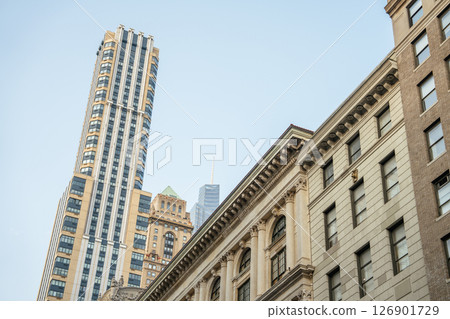 Tall skyscrapers rise behind older, classical buildings in this view of Midtown Manhattan. The contrast between architectural styles highlights New York City's evolving skyline. 126901729