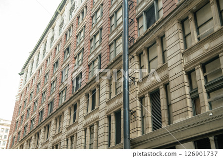 A detailed view of a classic red brick and beige stone building in New York. The architecture features large windows and vintage design. 126901737