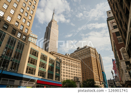 The tall spire of the Empire State Building pierces the sky above Midtown. Buildings of various eras create a diverse architectural scene below. 126901741