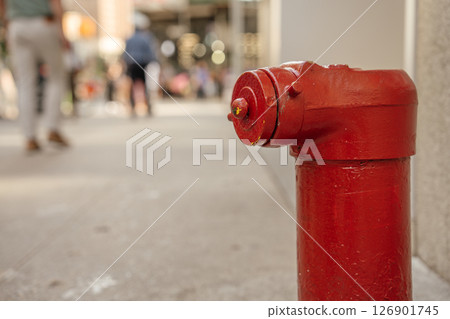 A vibrant fire hydrant is prominently shown with a blurred urban scene behind. The image captures the texture and color of the hydrant in detail. 126901745