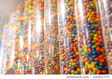Tall transparent tubes are filled with layers of bright, colorful candies. The close-up image captures the vibrant textures and colors of the popular chocolate treat. 126901774