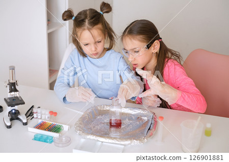 Girls mix liquids in a test tube doing school experiments Girls mix liquids in a test tube doing school experiments 126901881