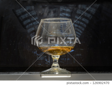 Whiskey glass or Brandy snifter stands on Laptop with laptop screen in the background. 126902470