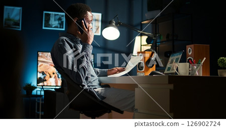 Male freelancer calling financial expert at home to discuss about monthly funds balance, increase profit with global investments. Young guy talking to advisor about capital resources. Camera A. Male freelancer calling financial expert at home to discuss about monthly funds balance, increase profit with global investments. Young guy talking to advisor about capital resources. Camera A. 126902724