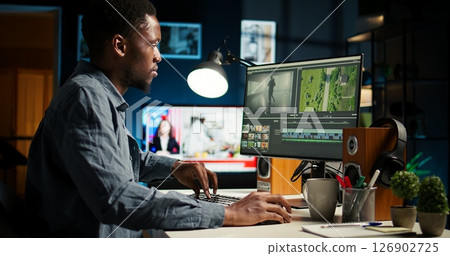 African american videographer works on editing film footage at home, doing freelance contract for post production scenes. Editor correcting white balance and color grading, pc software. Camera A. African american videographer works on editing film footage at home, doing freelance contract for post production scenes. Editor correcting white balance and color grading, pc software. Camera A. 126902725