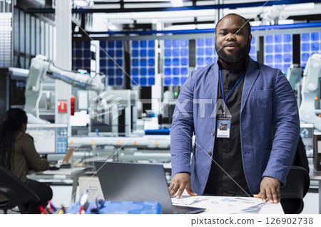 Black industrial engineer in a solar panel plant assesses system performance, playing a crucial role in monitoring efficiency and workplace safety. Renewable power with photovoltaics. 126902738