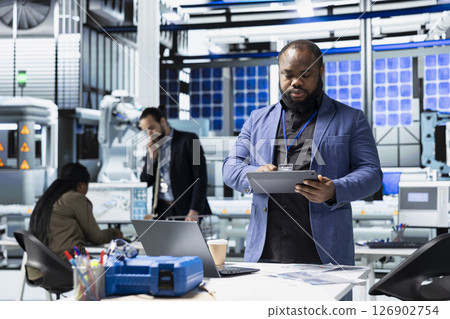 African american supervisor checking solar panel machinery and reviewing a checklist, playing a vital role in renewable energy production and assembly line. Efficient solar tech infrastructure. 126902754