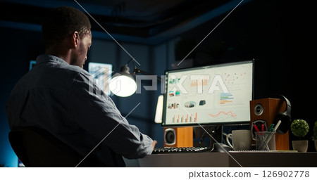 Network analyst studying digital commerce progression reports on computer, working at home to boost earnings and gain shareholder backing. Specialist analyzes company information. Camera A. Network analyst studying digital commerce progression reports on computer, working at home to boost earnings and gain shareholder backing. Specialist analyzes company information. Camera A. 126902778