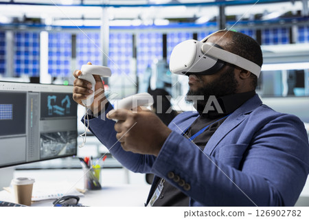 African american master engineer using VR headset to improve solar energy automation, eco friendly. Photovoltaics manufacturing plant specialist using virtual reality equipment, high tech. African american master engineer using VR headset to improve solar energy automation, eco friendly. Photovoltaics manufacturing plant specialist using virtual reality equipment, high tech. 126902782