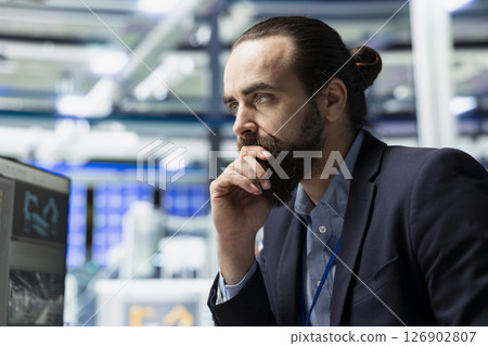 Male factory consultant observes production systems on a pc in a solar plant, providing expert feedback on efficiency, safety and sustainability aligned with green energy initiatives. 126902807