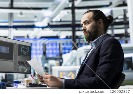 Male building contractor in a solar panel plant conducts a routine inspection, contributing to renewable energy development and maintaining high standards in engineering processes. 126902837