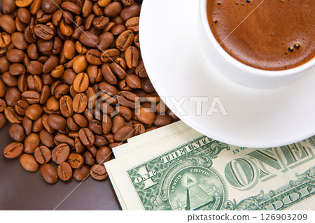 fresh cup of espresso resting on a saucer, with aromatic roasted coffee beans and dollar bills fresh cup of espresso resting on a saucer, with aromatic roasted coffee beans and dollar bills 126903209