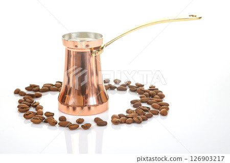 Elegant copper coffee pot with a brass handle paired with roasted coffee beans Elegant copper coffee pot with a brass handle paired with roasted coffee beans 126903217