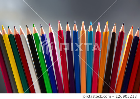 colored pencils in a neat line, displaying a rainbow of colors against a subtle gray background colored pencils in a neat line, displaying a rainbow of colors against a subtle gray background 126903218