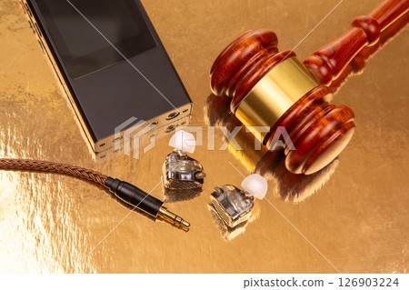 Wired earbuds, a black audio device, and a wooden gavel 126903224
