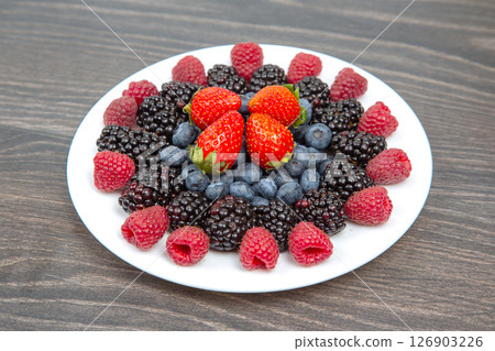 raspberries, blueberries and blackberries on a white plate. Vitamin and Diet Food 126903226