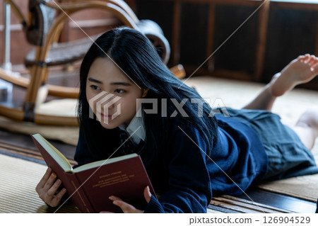 A high school girl lying down and reading a book A high school girl lying down and reading a book 126904529