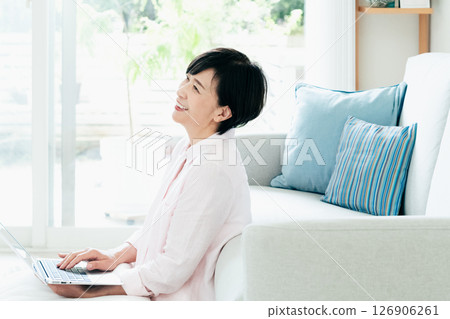 A middle-aged woman operating a computer in the living room A middle-aged woman operating a computer in the living room 126906261