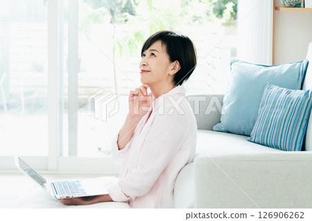 一位中年婦女在客廳操作電腦 126906262
