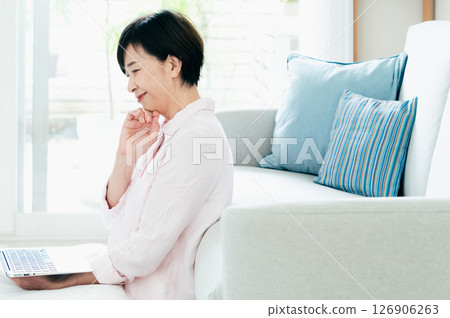 一位中年婦女在客廳操作電腦 126906263