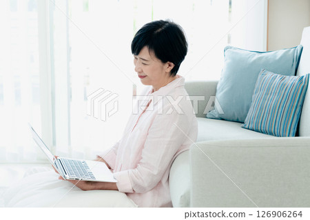 一位中年婦女在客廳操作電腦 126906264