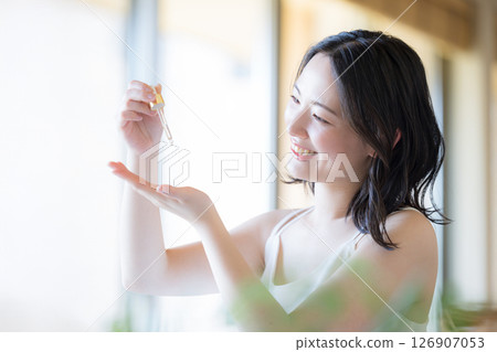 一位女士將乳液或精華液滴在手上 — — 美麗和美麗的形象 一位女士將乳液或精華液滴在手上 — — 美麗和美麗的形象 126907053