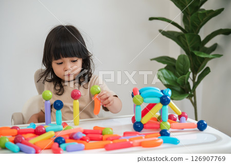 toddler girl playing colorful magnetic construction toy 126907769