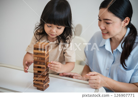 toddler girl with mother playing wooden block toy together toddler girl with mother playing wooden block toy together 126907771