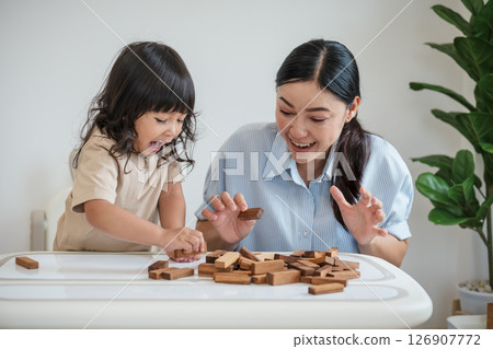 toddler girl with mother playing wooden block toy together and shocked with tower collapses 126907772