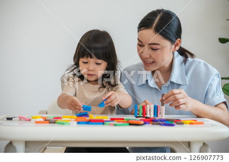 toddler girl and mother playing colorful wooden block toy or domino game together 126907773