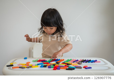 toddler girl playing wooden block toy or domino game 126907776