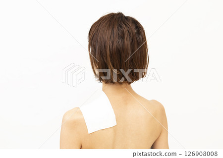 Back view of a woman with a compress on her shoulder 126908008