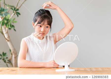 Children, girls, elementary school students, and junior high school students styling their hair while looking in the mirror (stray hairs, flyaway hairs, frizzy hairs) 126908383