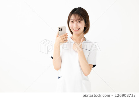 一個穿著白大褂的女人拿著智能手機 126908732