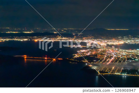 Aerial night view of San Francisco reveals a glowing street grid, Golden Gate and Bay Bridges shining across dark bay waters, low fog hugging the shoreline, and distant East Bay lights. California Aerial night view of San Francisco reveals a glowing street grid, Golden Gate and Bay Bridges shining across dark bay waters, low fog hugging the shoreline, and distant East Bay lights. California 126908947