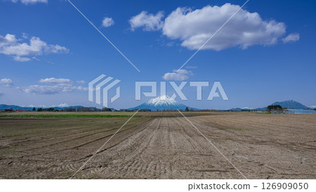 Mt. Shiribetsu, Mt. Yotei with remaining snow and the Niseko mountain range seen from the spring fields 126909050