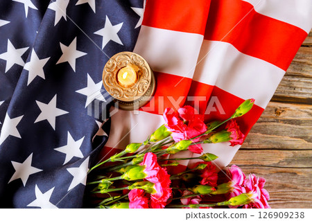 Celebration of patriotism featuring an American flag, pink flowers, candle on rustic wooden surface. 126909238