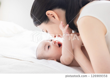 A mother gently touches her baby while they are in bed. A mother gently touches her baby while they are in bed. 126909358