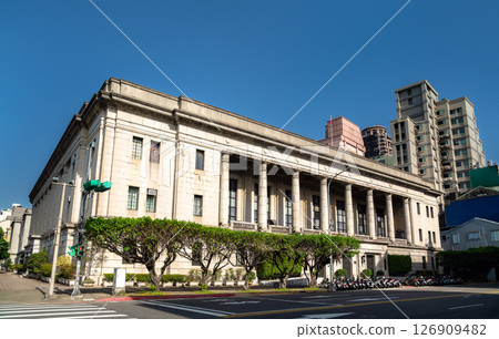 The neoclassical Bank of Taiwan headquarters stands on a sunny street corner in Taipei's Zhongzheng District, its tall granite colonnade and symmetrical stone facade contrasting with nearby modern The neoclassical Bank of Taiwan headquarters stands on a sunny street corner in Taipei's Zhongzheng District, its tall granite colonnade and symmetrical stone facade contrasting with nearby modern 126909482