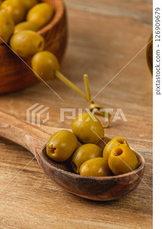 Olive varieties displayed in wooden bowls and spoon on rustic table Olive varieties displayed in wooden bowls and spoon on rustic table 126909679