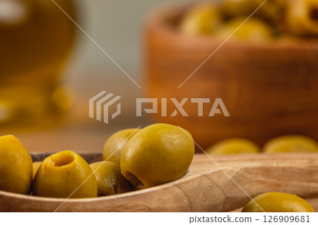 Delicious green olives in a wooden bowl and spoon on a rustic table Delicious green olives in a wooden bowl and spoon on a rustic table 126909681