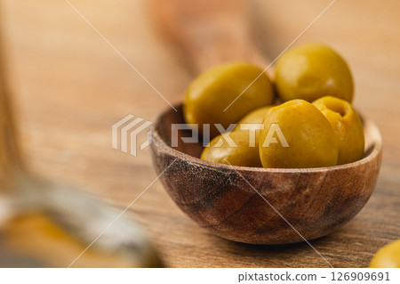 Green olives in a wooden bowl on a rustic table setting Green olives in a wooden bowl on a rustic table setting 126909691