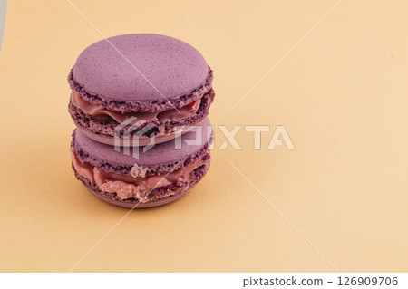 Purple macarons stacked on a yellow surface in a simple layout Purple macarons stacked on a yellow surface in a simple layout 126909706