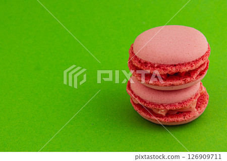 Delicious pink macarons stacked on bright green backdrop Delicious pink macarons stacked on bright green backdrop 126909711