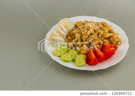 Delicious scrambled eggs served with vegetables and cheese 126909722